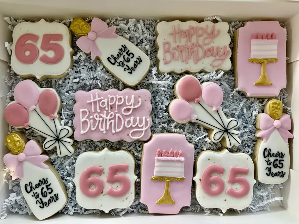 Pink and white 65th birthday cookies with balloons, cakes and Happy Birthday plaques